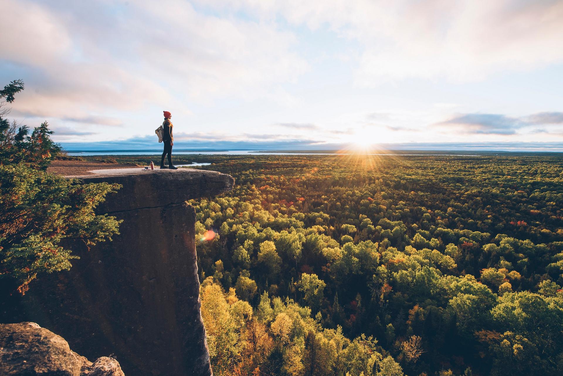 A hiker looks down at a river from a hill crest